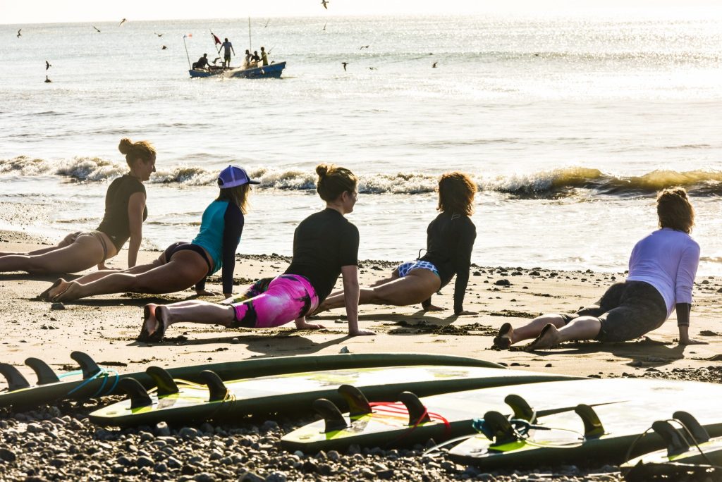 A group doing yoga by surf boards