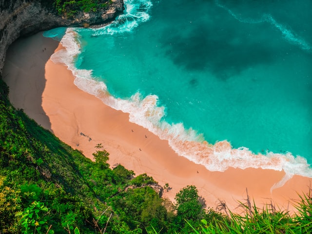 An aerial shot of a sandy beach with turquoise water 
