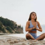 a woman doing yoga on the beach