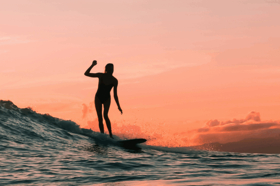 woman surfing at sunset
